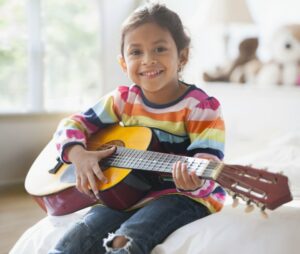 Little girl in a striped shirt holding a guitar