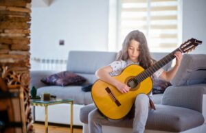 Little boy with long hair playing the guitar