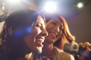 Two women sharing a microphone to sing