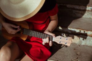 Close up of a woman in a red dress holding a ukulele