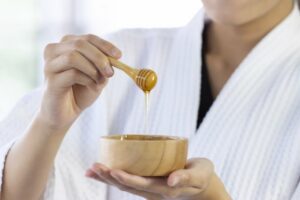 Closeup of woman's hands holding a bowl of honey