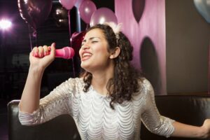Young woman in pink singing into a microphone