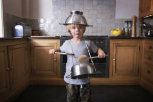 Little boy wearing pots and pans holding drum sticks