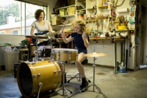 Little girl playing drums while her mom plays guitar
