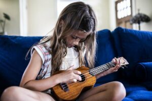 Little girl playing ukulele in her living room
