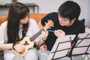 Male instructor showing student how to play ukulele