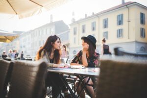 Two women seated at a café in Italy having a conversation