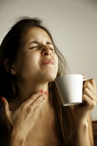 Woman with a sore throat sipping tea