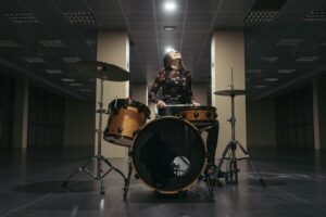 Young woman starring up into the lights while playing the drums