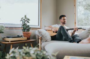 Man leaning back on his couch playing the guitar