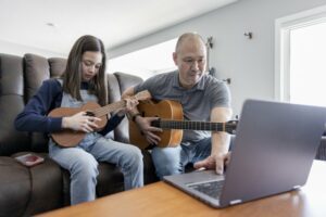 Father and daughter learning to play the ukulele