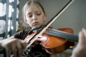 Little girl focusing on playing the violin