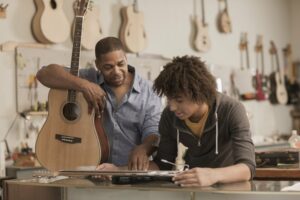Man and teenage boy examining a guitar at the music store