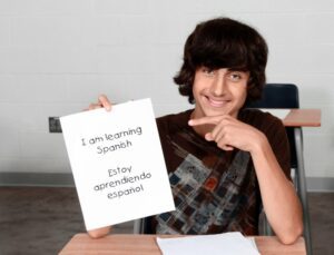 Teenage boy holding up a paper with Spanish translated