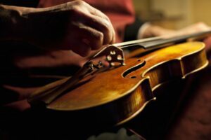Close up of a man plucking strings on a violin