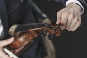 Close up of a man tuning a violin