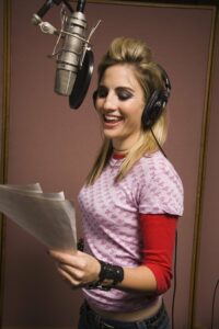 Female singer smiling in a recording booth