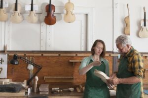 Two people discussing violin repair in a shop