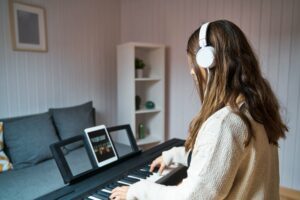 Young woman practicing the piano via online lesson