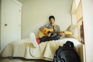 Teen boy playing the guitar in his room