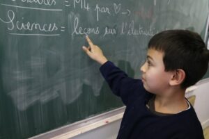 Little boy studying French written on a chalkboard