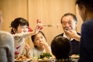 Family in Japan having dinner while holding up food with a fork