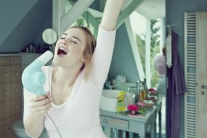 Girl singing happily into blow dryer