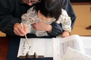 Father teaching his daughter Japanese calligraphy
