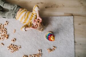 Little boy laying on the floor holding alphabet letters to his face