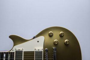 Close up of the bottom of a gold electric guitar