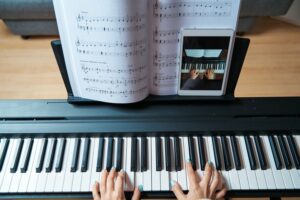 Close up of hands playing the piano along with an online lesson