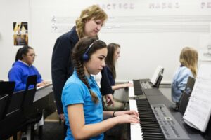 Female instructor helping a student play piano