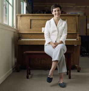 Female piano instructor sitting on a piano bench