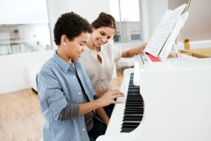 Female teacher showing male student to play piano