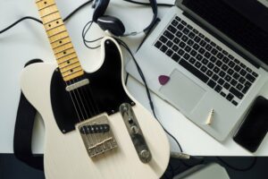 Top view of a guitar next to a laptop