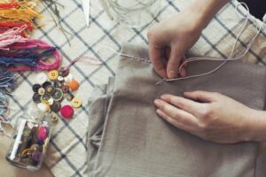 Close up of a woman sewing a button on some cloths