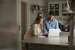 Smiling couple looking at a laptop in their kitchen