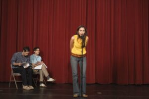 Young woman in a yellow top auditioning on a stage
