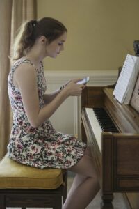 Young woman in a dress looking at sheet music on her phone