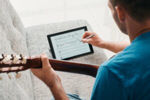 Man sitting down writing his own music on an iPad