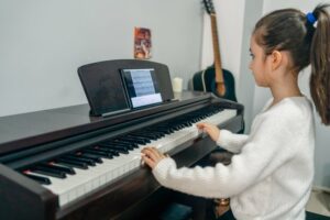 Little girl in a white sweater playing the piano