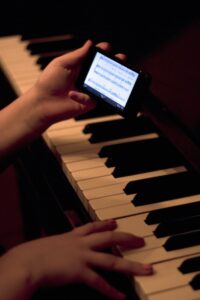 Close up of hands playing the piano and holding a phone