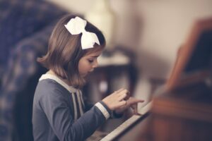 Little girl pressing keys on a piano