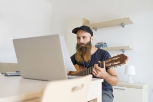Bearded man taking a guitar lesson online