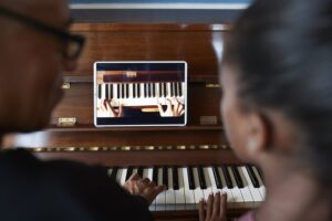 Back view of a father and daughter learning piano through an online app