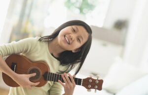 Little girl smiling playing the ukulele