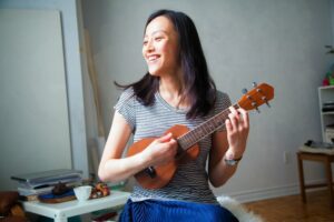 Young woman smiling playing the ukulele