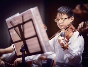 Little boy wearing glasses playing the violin
