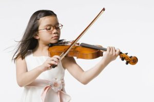 Little girl in a pink dress playing the violin