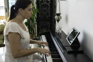 Woman in a striped shirt learning to play the piano with an online app
